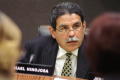 Photograph: [Michael Hinojosa with a microphone and nameplate bearing his name]