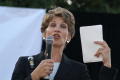 Primary view of [Laura Miller holding white papers and microphone]