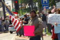 Primary view of [Male Protester Holding Bright Pink Sign and American Flag]