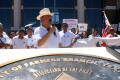 Primary view of [Man in a hat with a microphone addressing the crowd ]