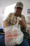 Photograph: [Man with plastic grocery bag and medicine]