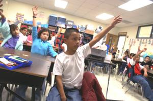 Primary view of object titled '[Students raise their hands during a class at Crockett Elementary]'.