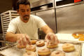 Primary view of [Man arranging donuts on tray]