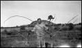 Photograph: [Photograph of a Man Holding Two Branches]