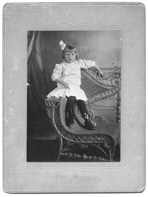 Primary view of object titled '[Unidentified girl in white dress on wicker chair]'.