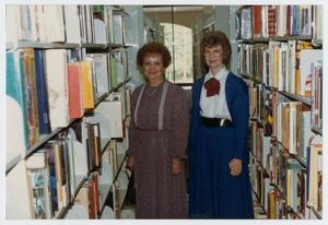 Primary view of object titled '[People Standing Between Library Bookshelves]'.