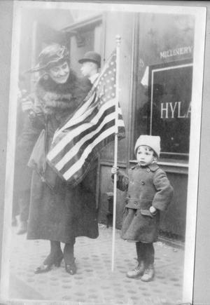 Woman Standing Next to Her Young Child Who is Holding a Flag