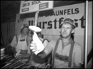 Primary view of object titled '[Bob Goebel Serving Sausage on a Stick]'.