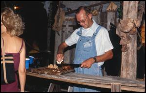 [Man Cutting Meat in Smokehouse]