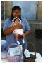 Photograph: [Woman Holds Baby During Health Fair]