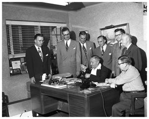 Men standing around desk