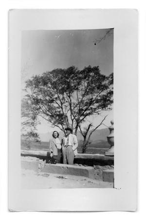 Vivian Osio and unknown man standing in front of a stone wall