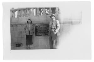 Unidentified woman and man standing next to a wall