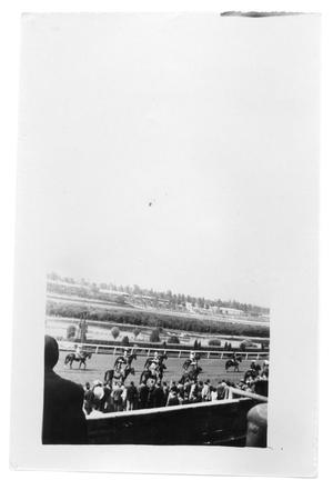 Men on their horses ride across the track in a stadium