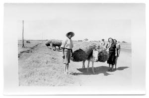 Two women stand next to a man and his mule