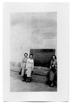 Three women in front of a stone building