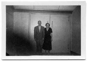 A man and woman standing in front of a pair of double doors