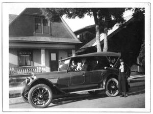 People inside a 1921 Oldsmobile parked outside a house