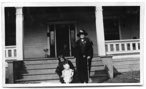 Two women and a child in front of the steps to a house