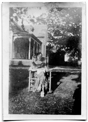 Woman sitting in a chair in the yard of a house