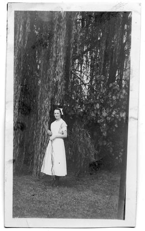 [Unidentified woman standing under a weeping willow]