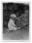 Photograph: [Child using a tool on a chair]