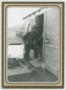 Photograph: [Charles Thomas Standing in the Doorway of a Hutment]