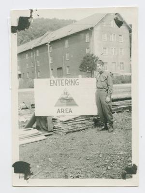 Primary view of object titled '[Arthur Fonjemie Standing by a 12th Armored Division Sign]'.