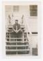 Photograph: [John Poulos Sitting on Barracks Steps]