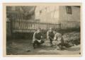 Photograph: [Roger Roy, Sergeant Pennell, and Ross Squatting by a House]