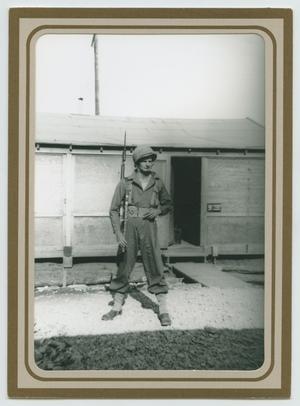 Primary view of object titled '[Charles Thomas Standing Outside of Hutment]'.