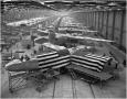 Photograph: Flag-Draped C-87 in a Factory of Military Airplanes