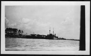 [Ship along the river bank. Some buildings on the bank. Location unknown.]