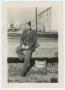 Primary view of [A Soldier Sitting on a Bridge Railing]