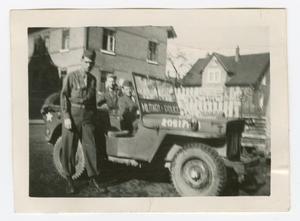 Primary view of object titled '[Leonard Stewart Standing by a Jeep]'.