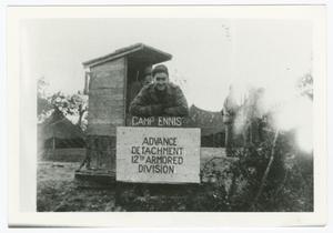 [Sergeant John Pilarski Leaning on a Camp Ennis Sign]