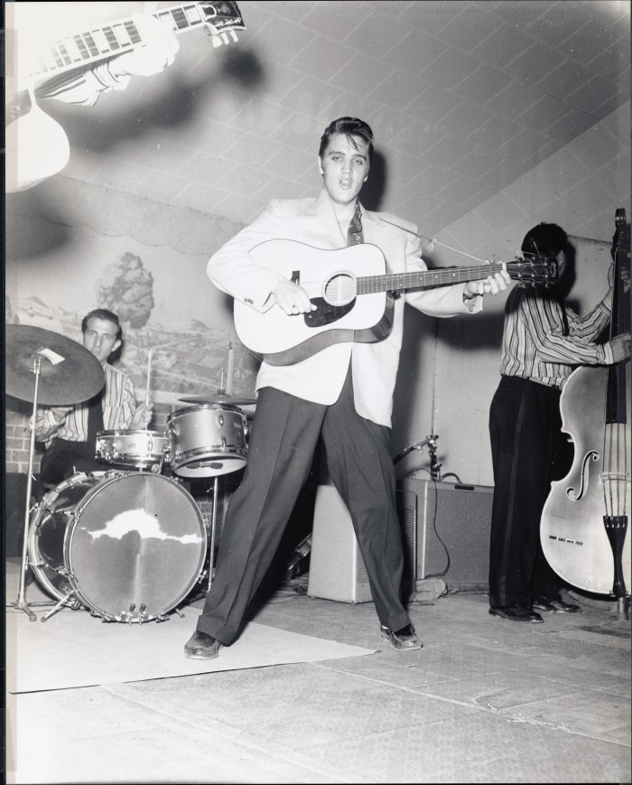 First side of: [Elvis Presley performing with the Blue Moon Boys], a photograph available in the The Portal to Texas History