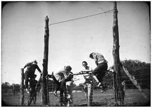 Primary view of object titled 'Men Climbing Over a Fence'.