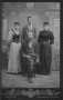 Photograph: [Four people. Man sitting down is scratched out in the picture.]