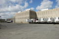 Photograph: [Five Semi Trucks Behind Building]