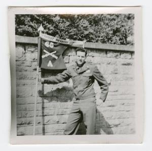 Primary view of object titled '[Lowell Flamm Holding a Combat Infantry Company Pennant]'.