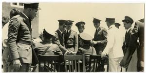 Men in Uniforms, Some Standing and Shaking Hands with Some Sitting