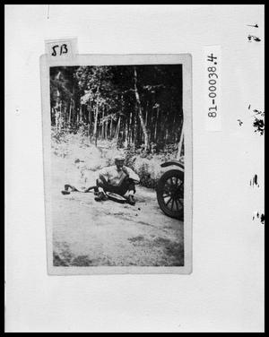 Primary view of object titled 'Man and Child Eating by Car on Side of Road'.