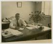 Photograph: [Photograph of M. Thelin Sitting at Desk]