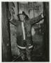 Photograph: [Firefighter Standing in Charred Building]