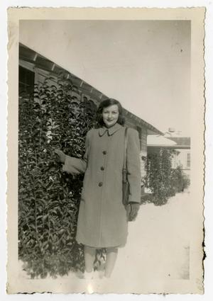 [Woman in an Overcoat Standing by a Bush]