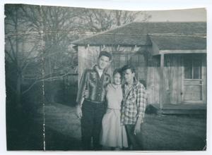 Primary view of object titled '[Roger Cook, Muriel June, and Jimmy Perdue by a House]'.