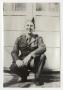 Photograph: [Soldier Squatting in Front of Building]