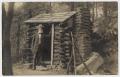 Primary view of [Postcard with Old Man Leaning on a Log Cabin]