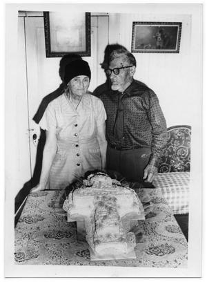 [Mr. and Mrs. Otto Lindig Standing Behind a Cake]
